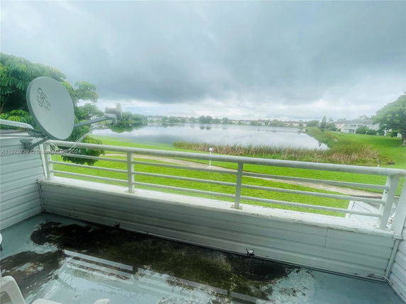 View from a balcony facing a lake with surrounding greenery and houses.