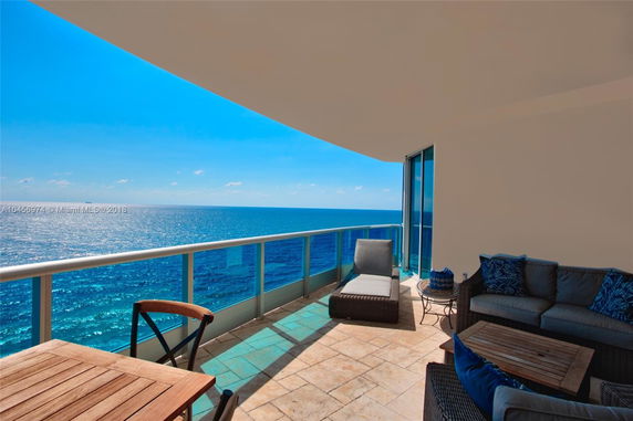Balcony view overlooking the ocean with outdoor furniture.