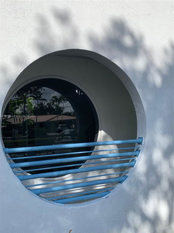 Circular window on a building wall with blue bars.