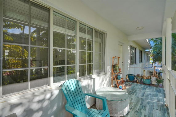 Outdoor view of a building's porch with chairs and a table.