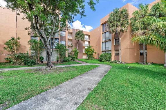 Front view of a multi-story residential building with large windows and a walkway.