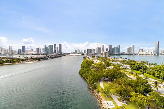 Panoramic view of a city skyline with waterway and bridge.