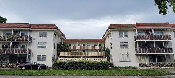Front view of a three-story residential building with balconies and a red roof.