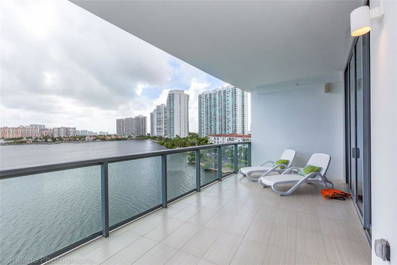 Panoramic view from a balcony overlooking water and high-rise buildings.