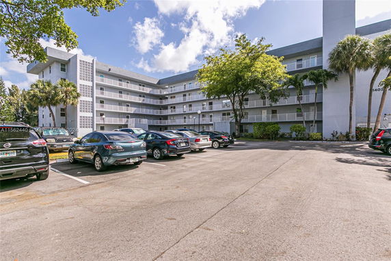 Front view of a multi-story residential building with a parking lot.