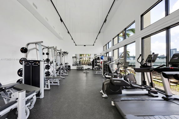 Indoor gym area with various exercise equipment and large windows.