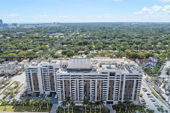 Aerial view of a large multi-story building with urban green surroundings.
