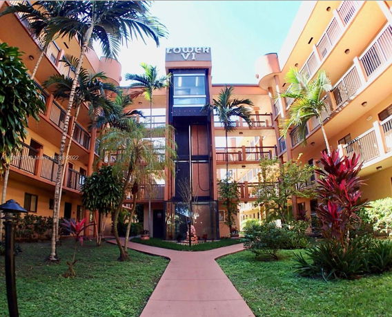 Front view of a multi-story residential building with balconies and garden area.