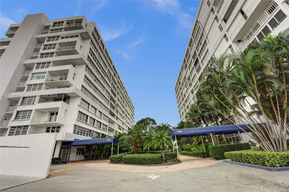 Front view of a multi-story residential building with balconies and a covered entrance.