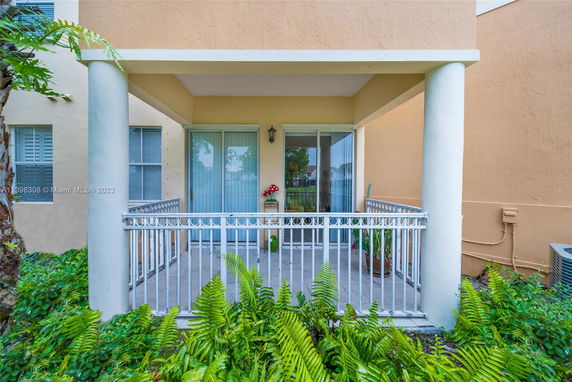 View of a patio area with sliding glass doors and railing, surrounded by plants.