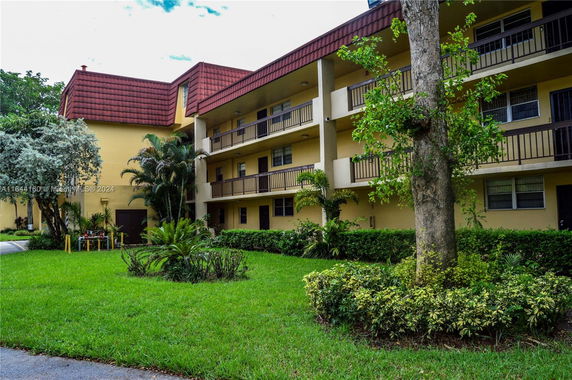 Front view of a multi-story building with balconies and a green lawn.