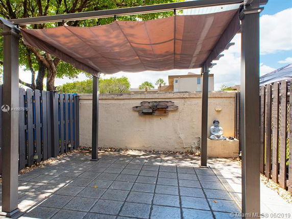 Outdoor patio area with a pergola and paved flooring.