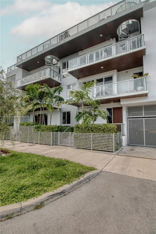 Front view of a modern multi-story building with balconies and glass railings.