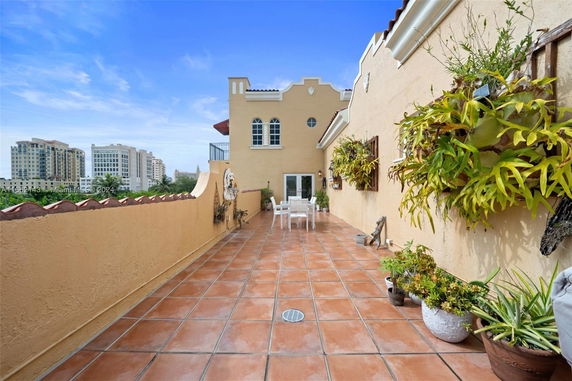 Terracotta-tiled rooftop patio with potted plants and outdoor seating.