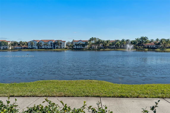 View of apartment buildings across a lake with a fountain.