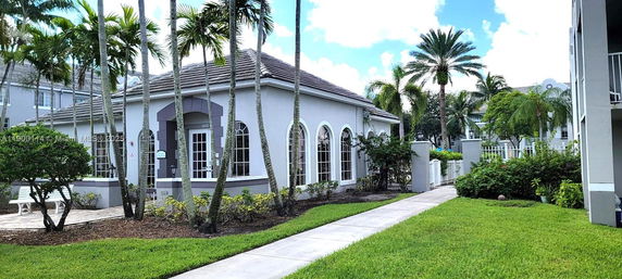 Front view of a single-story building with arched windows and palm trees.
