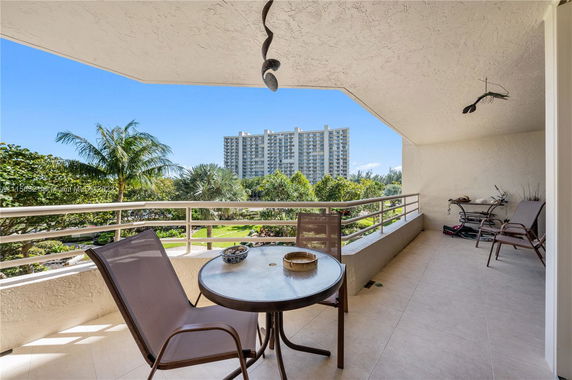 Balcony view of surrounding greenery and a distant high-rise building.