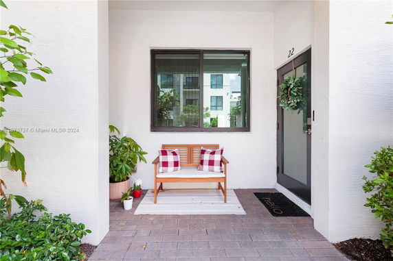 Front view of a house entrance with a bench and decorative plants.