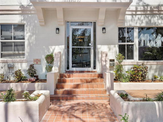 Front view of a building with stairs leading to the entrance and potted plants on either side.