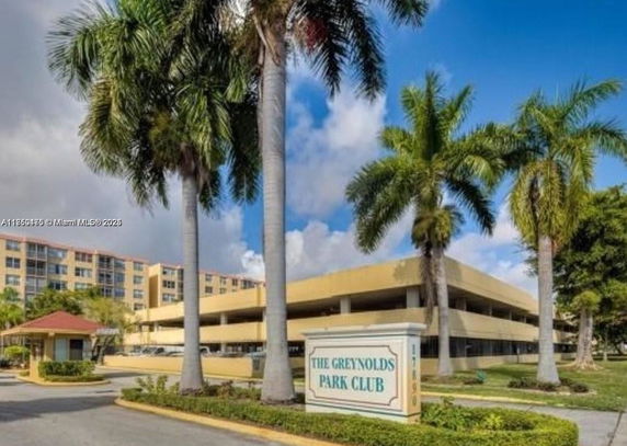 Front view of a multi-story building with palm trees and an entrance sign.