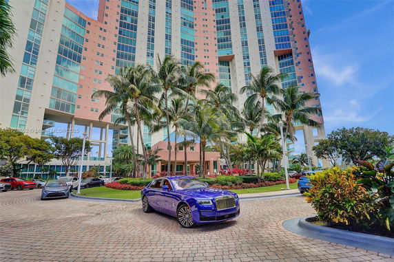 Front view of a high-rise building with palm trees and a circular driveway.