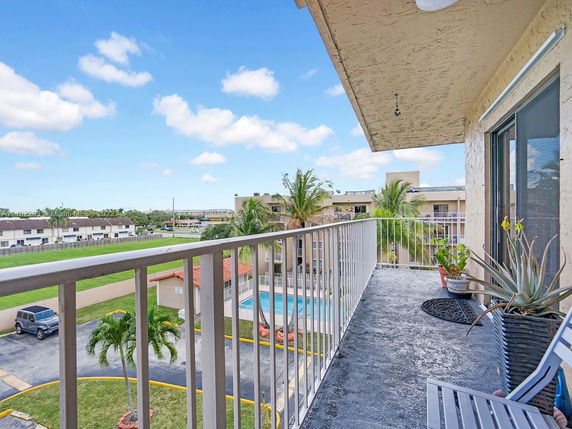 View from a balcony overlooking a swimming pool and residential buildings.