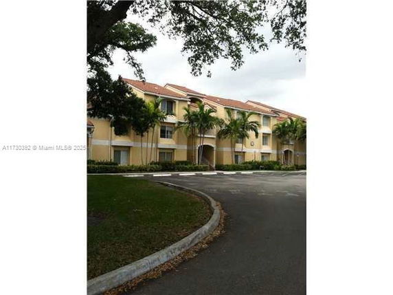 Front view of a multi-story residential building with palm trees.