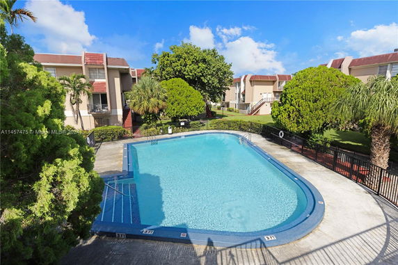 Outdoor swimming pool surrounded by trees and apartment buildings.