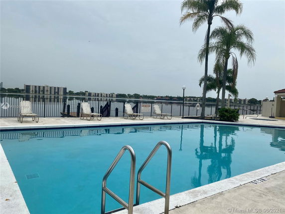 Outdoor swimming pool with lounge chairs and view of buildings across a body of water.