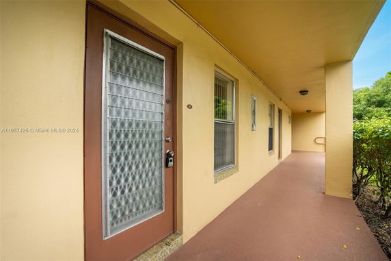 Exterior view of a building corridor with yellow walls and a glass door.