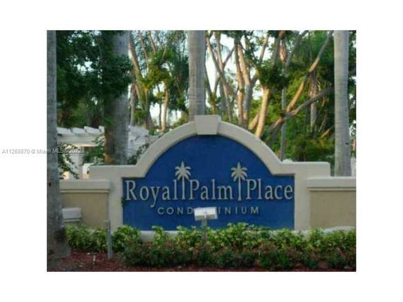 Signage for Royal Palm Place Condominium surrounded by trees and plants.