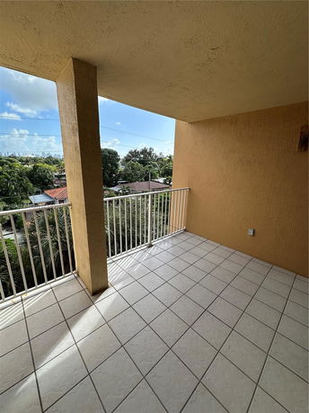 Balcony view overlooking surrounding area with houses and trees visible.