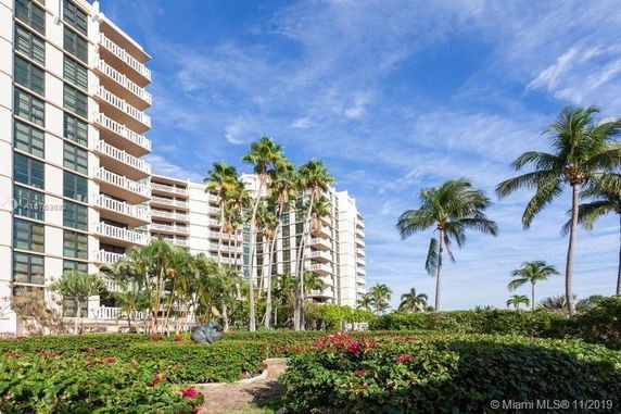 View of a residential building with balconies and surrounding palm trees.