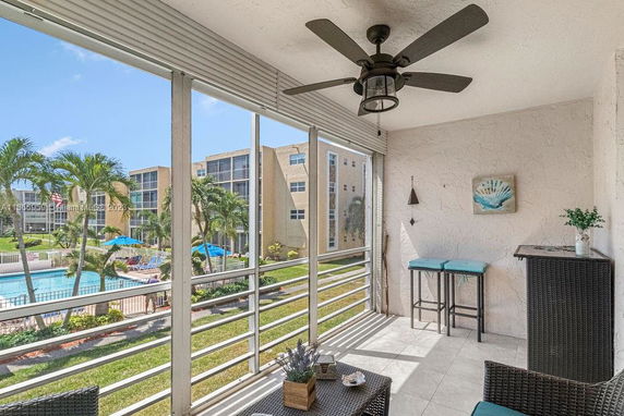 View from a balcony overlooking a swimming pool and apartment buildings.