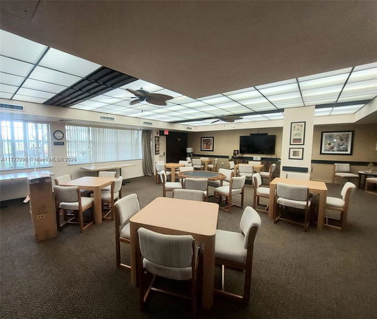 Indoor recreation area with tables and chairs, ceiling fan, and artwork on the walls.