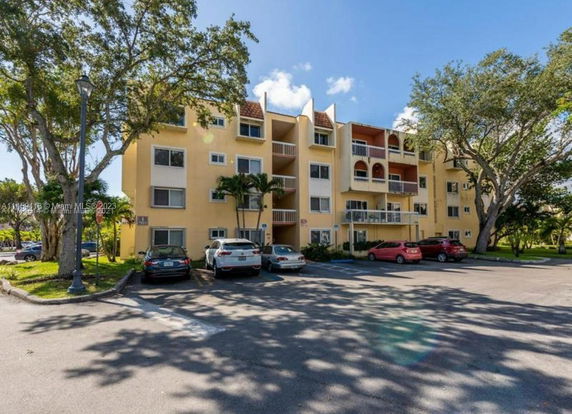 Front view of a multi-story apartment building with adjacent parking area.