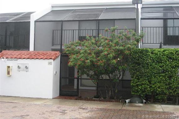 Front view of a two-story townhouse with a screened balcony and brick driveway.