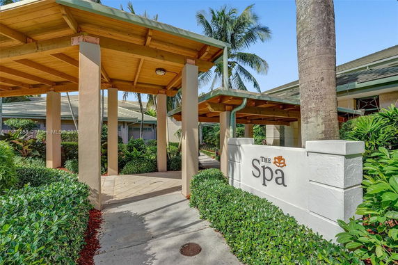 Front view of a spa entrance with wooden pergola and surrounding greenery.
