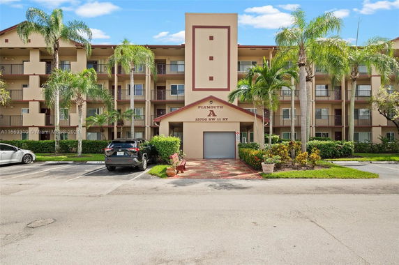 Front view of a multi-story apartment building with balconies and a driveway.