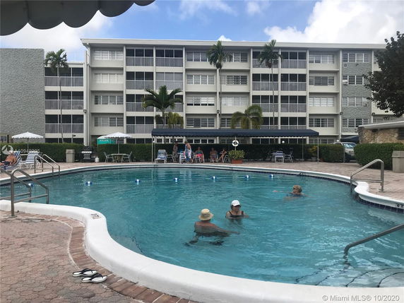 View of a multi-story residential building with a swimming pool in the foreground.