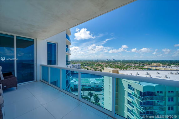 Balcony view from a high-rise building overlooking a cityscape.
