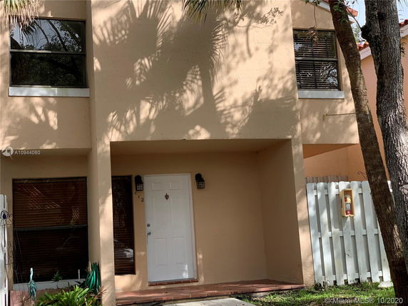 Front view of a two-story house with beige exterior and white front door.