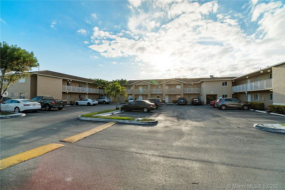 Outdoor parking area in front of a two-story apartment building.
