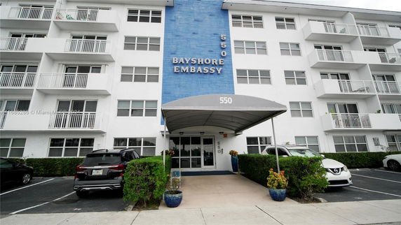 Front view of a multi-story building named Bayshore Embassy with balconies and a covered entrance.