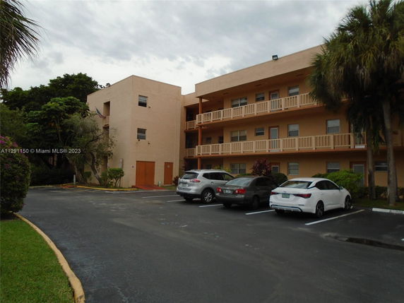 Front view of a multi-story building with balconies and parking area.