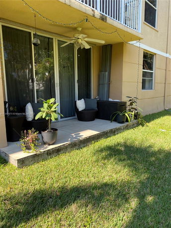 View of a house's patio area with potted plants and outdoor seating.