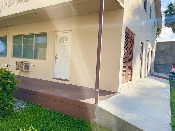 Front view of a two-story building with a small porch and white door.