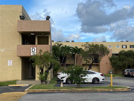 Front view of a multi-story building with a parking area in front.