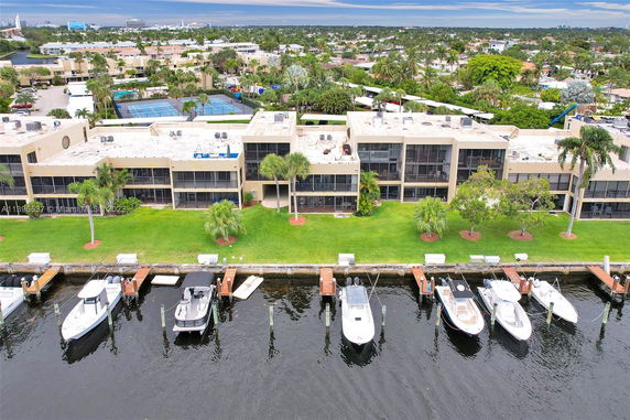 Aerial view of a waterfront residential building with boats docked nearby.