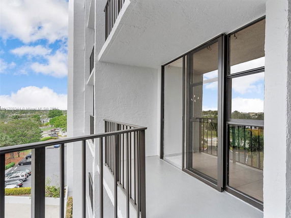 Balcony view from a multi-story building with glass sliding doors.